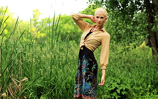 woman wearing brown long-sleeved shirt with black and green floral dress standing near green grass during daytime photo